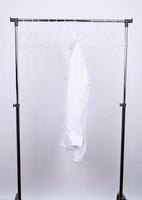 Weißes zerknittertes Herrenhemd, das an einem Metallbügel hängt foto