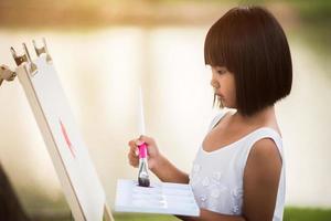 Künstlerin des kleinen Mädchens, die ein Bild im Park malt