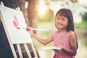 Künstlerin des kleinen Mädchens, die ein Bild im Park malt foto