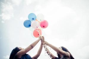 glückliche Gruppenfreundinnen, die bunte Luftballons an einem Park halten foto