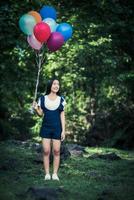 junges Mädchen, das bunte Luftballons in der Natur hält foto