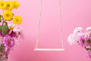 eine Schaukel mit Chrysanthemenblüten als Ständer für Ihr Kosmetikprodukt. kreatives Podium oder Sockelfederkonzept foto