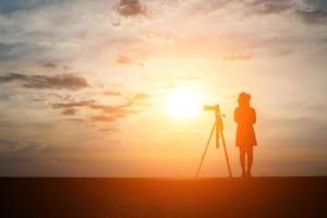 Silhouette eines Fotografen, der bei Sonnenuntergang schießt foto