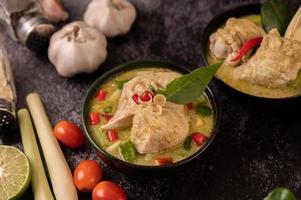 grünes Currygericht mit Huhn, Chili und Basilikum sowie Tomate und Limette