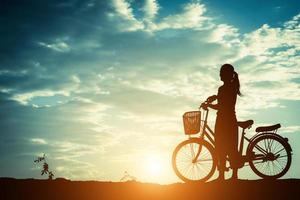 Silhouette einer Frau mit einem Fahrrad und schönem Himmel foto