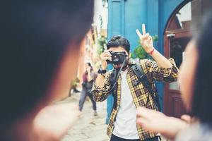 junger Mann, der Bilder seiner Freunde macht, während er zusammen im Stadtgebiet reist foto