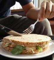 Person, die vorbereitet, Sandwich zu schneiden foto