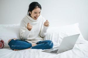 eine junge Frau, die glücklich auf ihrem Laptop spielt