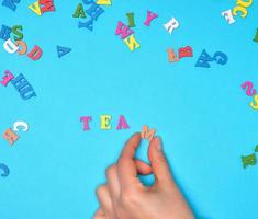 weibliche hand und bunte holzbuchstaben des englischen alphabets foto