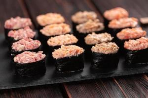 satz von gunkan maki sushi mit verschiedenen arten von fischlachs, kammmuschel, barsch, aal, garnelen und kaviar auf holztischhintergrund. Sushi-Menü. japanisches Sushi-Set Gunkans foto