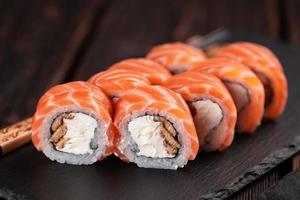 Sushi Roll Philadelphia mit Lachs und Aal und Frischkäse auf schwarzem Hintergrund Nahaufnahme. Sushi-Menü. japanisches lebensmittelkonzept foto
