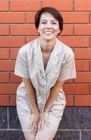 Fröhliche Frau im Haus tragen Pyjama Outdoor Backsteinmauer Hintergrund Emotionen - Nachtwäsche und Homewear-Konzept foto