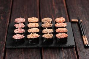 satz von gunkan maki sushi mit verschiedenen arten von fischlachs, kammmuschel, barsch, aal, garnelen und kaviar auf holztischhintergrund. Sushi-Menü. japanisches Sushi-Set Gunkans foto