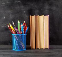 Bücherstapel und ein blaues Schreibwarenglas mit bunten Holzstiften foto