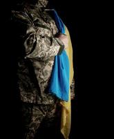 Der ukrainische Soldat hält die gelb-blaue Flagge des Staates in der Hand foto