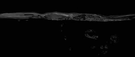 flüssige Oberflächenlinie zwischen Unterwasser und über Wasser mit schwarzem Hintergrund. foto