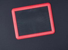 leere Kreidetafel im roten Rahmen auf schwarzem Hintergrund foto