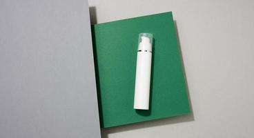 weiße Plastikflasche mit Kosmetikspray auf grüngrauem Hintergrund foto