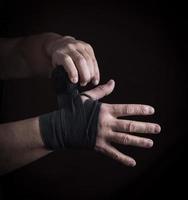 Mann wickelt seine Hände in schwarze Textilbandage foto