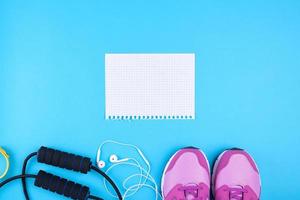 leeres weißes blatt papier, rosa sportturnschuhe und springseil auf blauem hintergrund foto