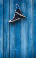 Paar blaue Turnschuhe an einer Holzwand foto