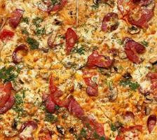 gebackene runde Pizza mit geräucherten Würstchen, Champignons, Tomaten, Käse und Dill foto