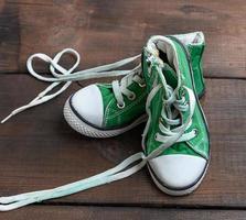 abgenutzte alte textilgrüne Turnschuhe mit ungebundenen weißen Schnürsenkeln foto