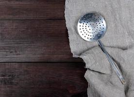 alter Küchenskimmer aus Eisen auf einer grauen Leinenserviette foto