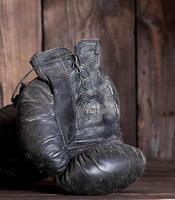 Paar sehr alte schäbige Boxhandschuhe aus schwarzem Leder foto