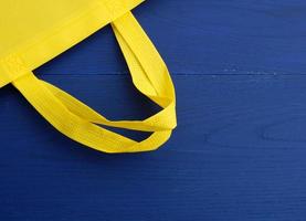 wiederverwendbarer gelber Viskosebeutel auf blauem Holzhintergrund foto