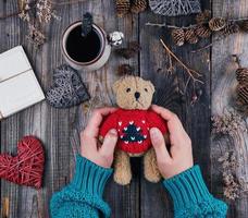 frauenhände in einem grünen pullover halten einen alten teddy-braunbären foto