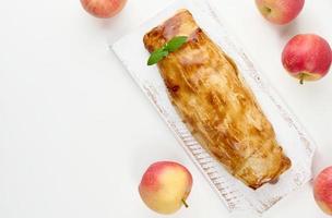 Gebackener Strudel mit Äpfeln auf einem weißen Holzbrett, leckeres Dessert foto