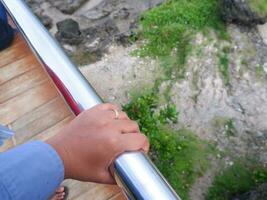 die Hand der Frau, die die Eisenbarriere der Brücke hält, Blick von oben foto