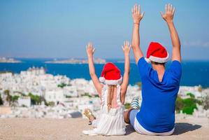 kleines mädchen und glücklicher vater in weihnachtsmützen genießen weihnachtsferien mit schöner aussicht foto