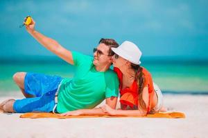 glückliches Paar, das im Urlaub ein Selbstfoto am Strand macht foto