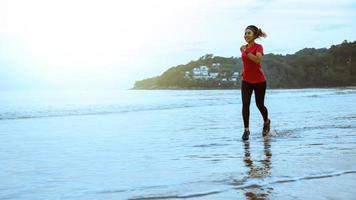 Frau joggt morgens am Strand. Entspannen Sie sich beim Meeresspaziergang. Aufspringen und Spaß beim Training. foto
