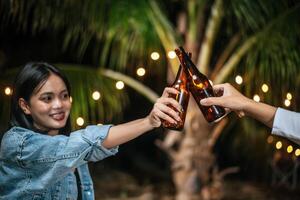 porträt glücklicher asiatischer freunde, die zusammen eine dinnerparty haben - junge leute, die biergläser abendessen im freien anstoßen - menschen, essen, trinken lebensstil, neujahrsfeierkonzept. foto