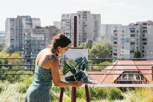 junger Künstler malt vor dem Hintergrund der Stadt foto