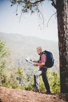 Wanderer mit Karte und großem Reiserucksack zum Berg foto