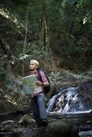 Abenteuermann, der Karte auf einem Bergweg beobachtet foto