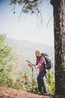 Wanderer mit Karte und großem Rucksack, der zum Berg reist foto