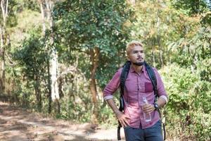 glücklicher Hipstermann-Tourist, der im Naturwald wandert foto