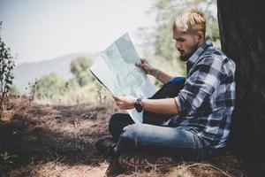 Wanderer entspannend durch Baum, der Karte betrachtet foto