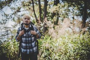 junger Mann, der mit einem Rucksack in der Natur reist foto
