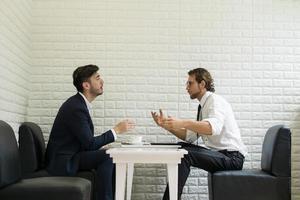 junger Geschäftsmann, der mit Kollegen in einer modernen Geschäftslounge spricht foto