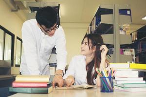 junge asiatische Studenten in der Bibliothek lesen gemeinsam ein Buch foto