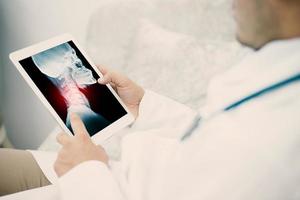 medizinischer junger männlicher Arzt, der Lungenröntgenogramm auf Tablette in Klinik erforscht foto