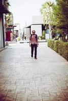 Porträt eines gutaussehenden Hipster-Mannes in Jeans und Sonnenbrille zu Fuß foto