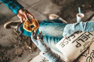 Bettler unter der Brücke mit Papphilfeschildern, die Brot annehmen foto