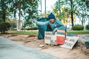 Ein Mann sitzt und bettelt mit Obdachlosen. Bitte helfen Sie foto